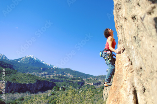 Guy climbing in Greece and beautiful forest and cliff landscape on the background