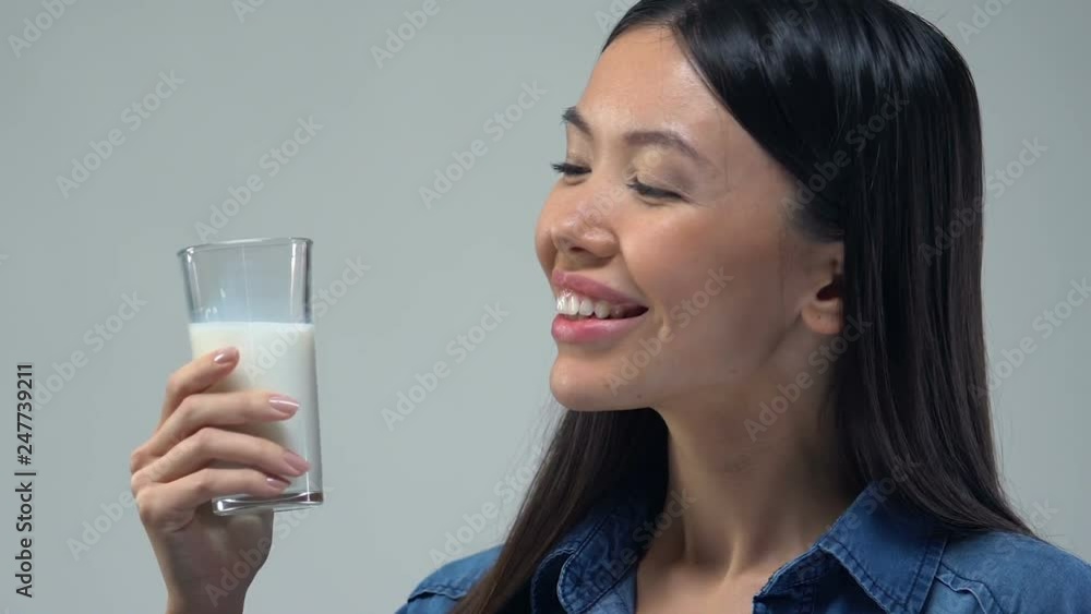Beautiful Asian woman drinking glass of milk, healthy diet, essential nutrients Beautiful Asian woman drinking glass of milk, healthy diet, essential nutrients
