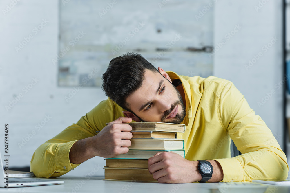 Obraz premium tired man lying on books in modern office