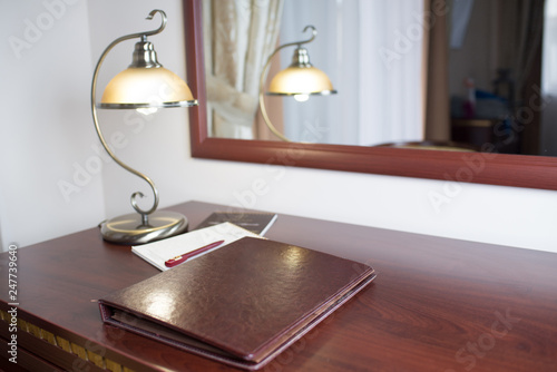 A work place with table, chair, table lamp and big notebook indoors