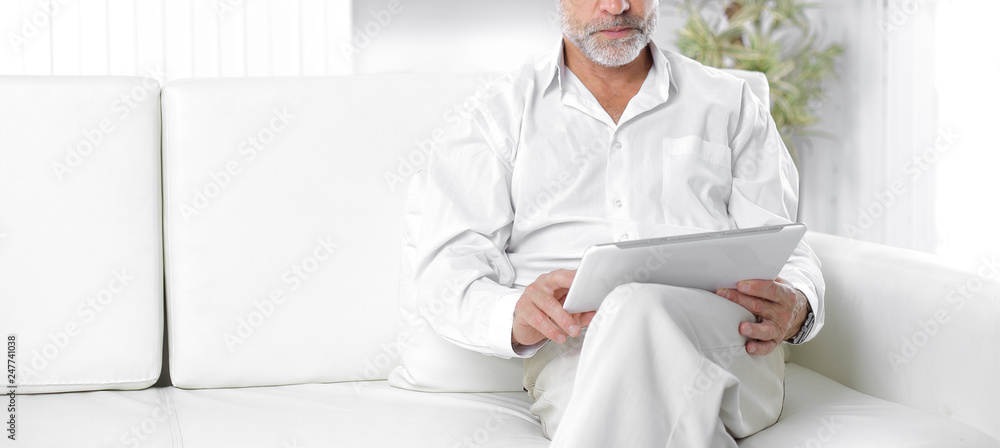 senior businessman with digital tablet sitting on sofa