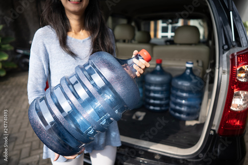 woman put a gallon of water in the car trunk at home. wanted to purchase the refill or by the new one photo