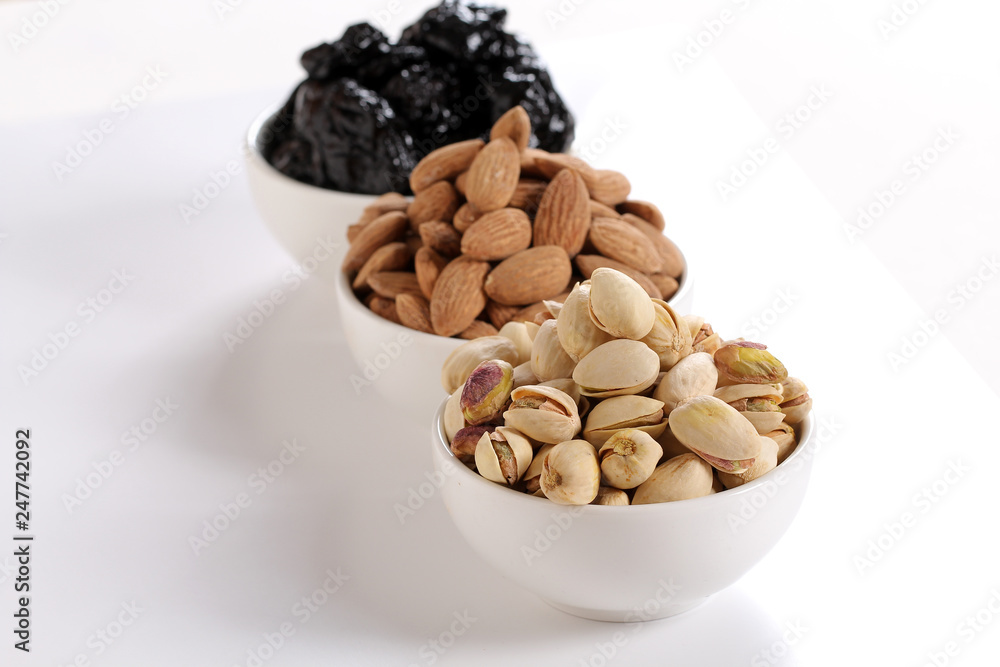 Assorted nuts on white, dry fruits, mix nuts, roasted almond, prunes, pistachio Assorted nuts on white, dry fruits, mix nuts, roasted almond, prunes, pistachio