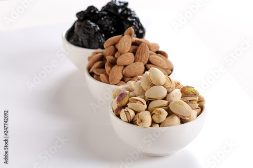 Fototapeta Naklejka Na Ścianę i Meble -  Assorted nuts on white, dry fruits, mix nuts, roasted almond, prunes, pistachio