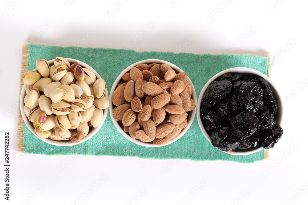 Assorted nuts on white, dry fruits, mix nuts, roasted almond, prunes, pistachio Assorted nuts on white, dry fruits, mix nuts, roasted almond, prunes, pistachio