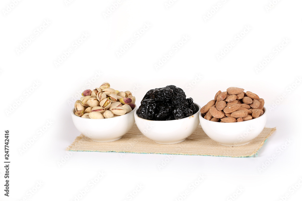 Assorted nuts on white, dry fruits, mix nuts, roasted almond, prunes, pistachio Assorted nuts on white, dry fruits, mix nuts, roasted almond, prunes, pistachio