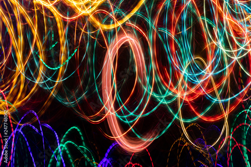 Abstract background of glowing multicolored twisted lines on black background.