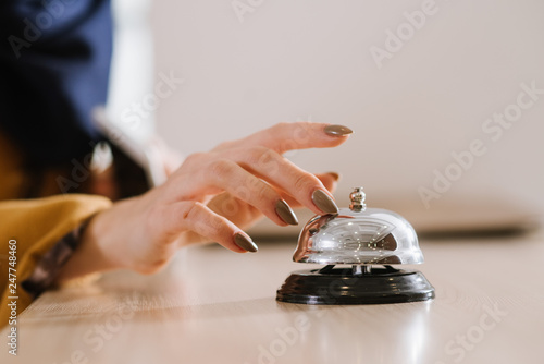 A womans hand on the hotel bell at the reception