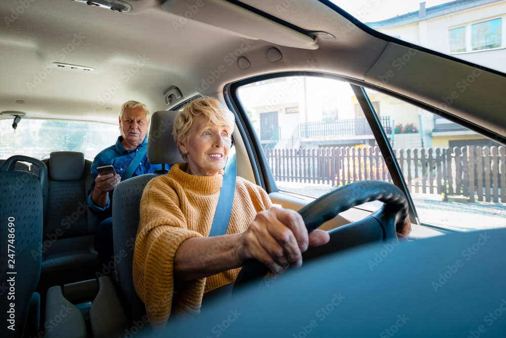 Senior uber driver sitting in a car with male passenger