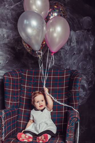 Close up portrait of cute adorable cheerful infant baby girl in dress playing with baloons, celebrating happy birthday. Baloons background, party concept. Childhoood, cute kid, happiness concept photo