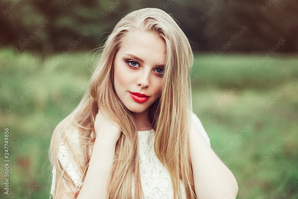 Naklejka premium Close up natural portrait of young happy cute cheerful caucasian beautiful girl witn long natural blondie hair walking in park in summer evening