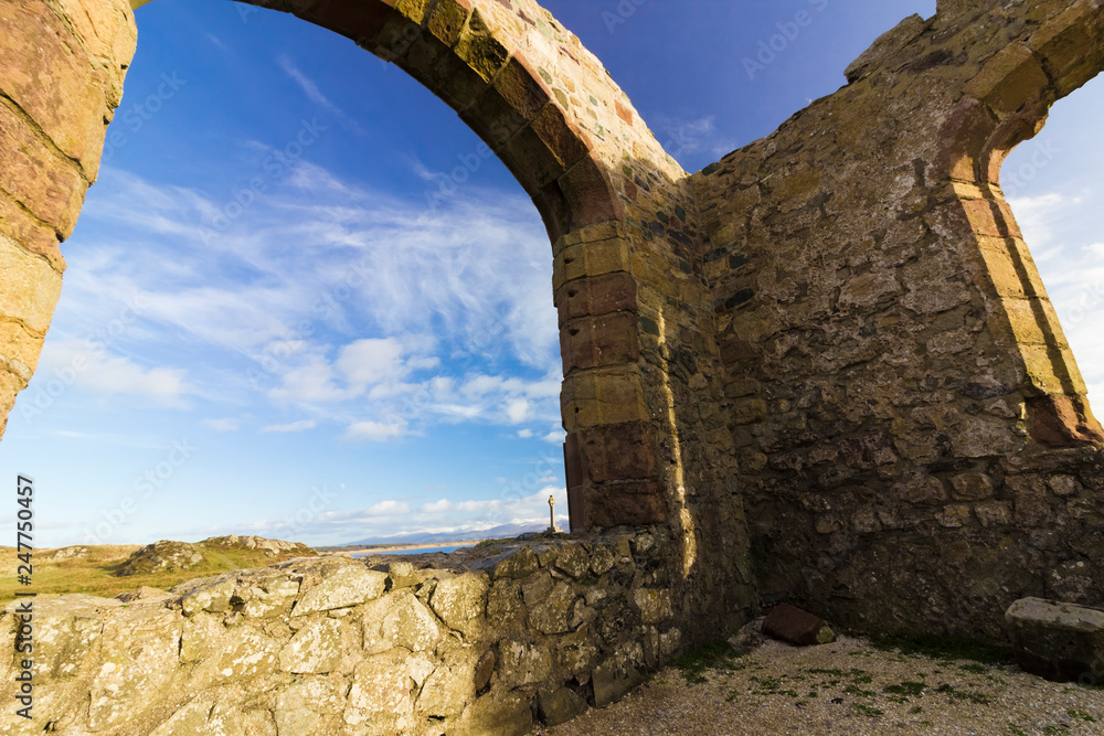 Fototapeta premium View from the remains of St Dwynwen's Church on Llanddwyn Island with the Snowdonia Mountain Range behind, Anglesey, North Wales