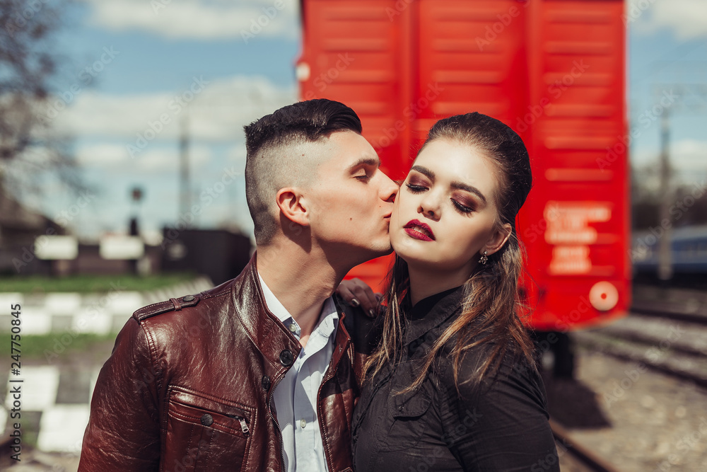 Romantic love in railway station near red railway carriage in summer. Young gorgeous sexy hipster couple outdoors Romantic love in railway station near red railway carriage in summer. Young gorgeous sexy hipster couple outdoors