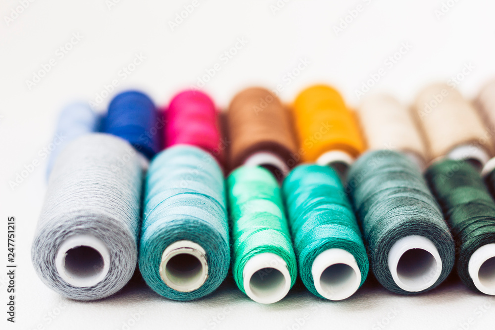 Colored sewing thread coils on white background with copy space for text.