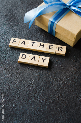 Happy Father's day greeting card with decorated gift box on dark background.