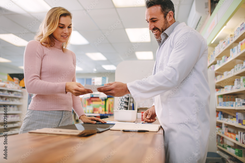 Chemist taking prescription from customer at pharmacy Chemist taking prescription from customer at pharmacy