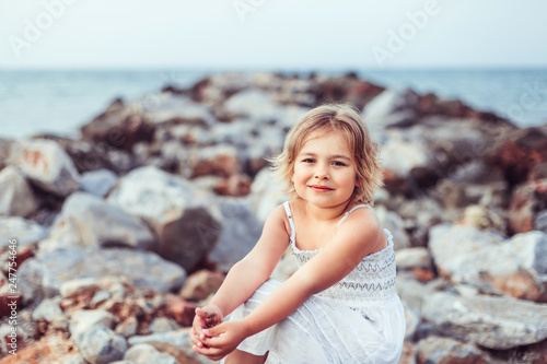 Cheerful happy emotional caucasain pretty girl on the beach coast of the ocean with rocks landscape having fun photo