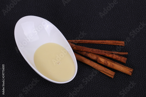 Condenced milk in the bowl with sinnamon and pastry photo