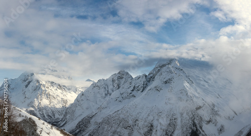 snowy mountain peaks in winter day with blue sky in Dombay, Caucasus, Karachay-Cherkessia, Russia