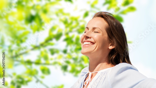 people and leisure concept - happy smiling woman enjoying sun over green natural background