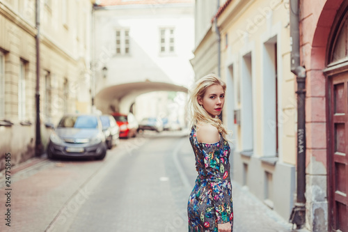 Street stylsh portrait of young blodnie cheerful girl walking in the old town. Vacation, travelling, beauty concept
