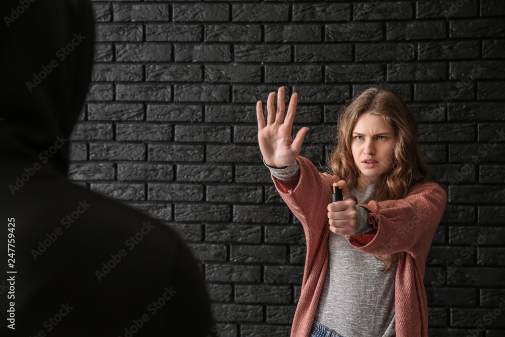 Woman with pepper spray defending herself against thief on dark background  Photos | Adobe Stock