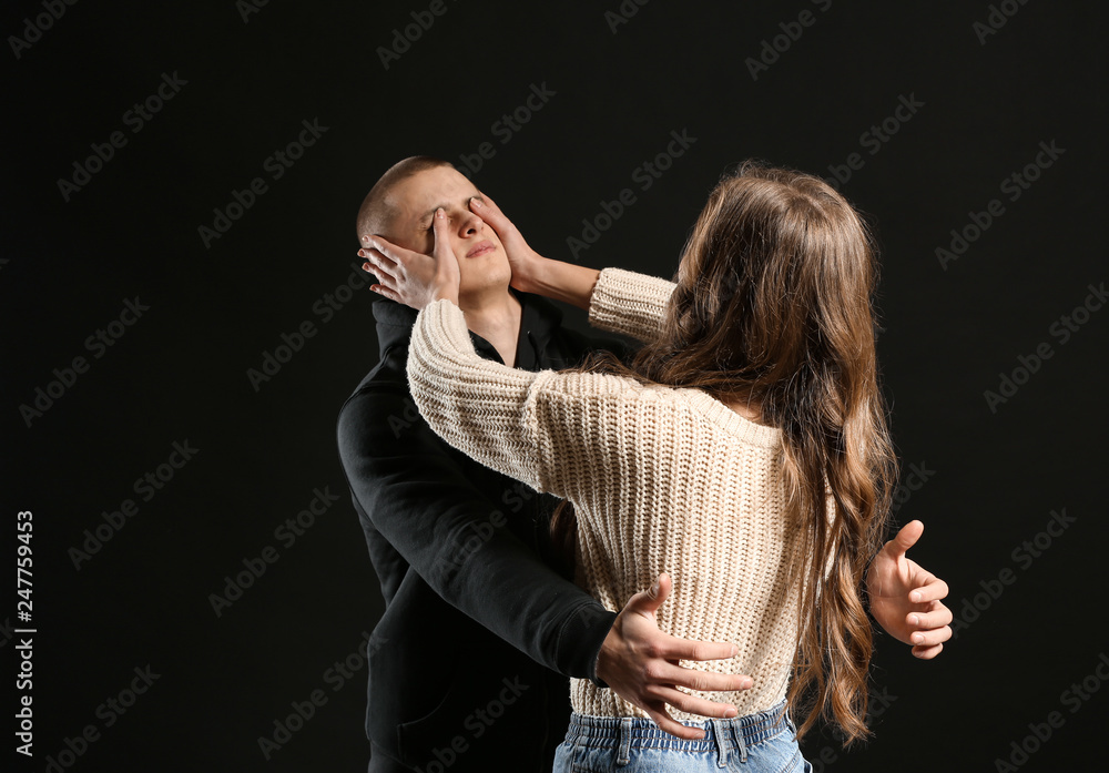 Young woman defending herself from attack by thief on dark background - obrazy, fototapety, plakaty 