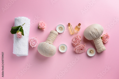 Spa composition with herbal bags  candles  flowers and towel on color background