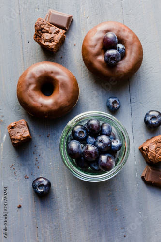 Donut mit Schokoglasur und Blaubeeren auf blauen Holz
