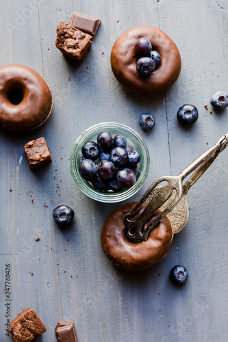 Donut mit Schokoglasur und Blaubeeren auf blauen Holz
