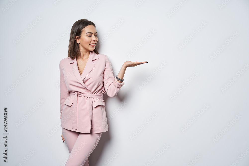 Woman wearing pink suit holding copy space on the palm Woman wearing pink suit holding copy space on the palm