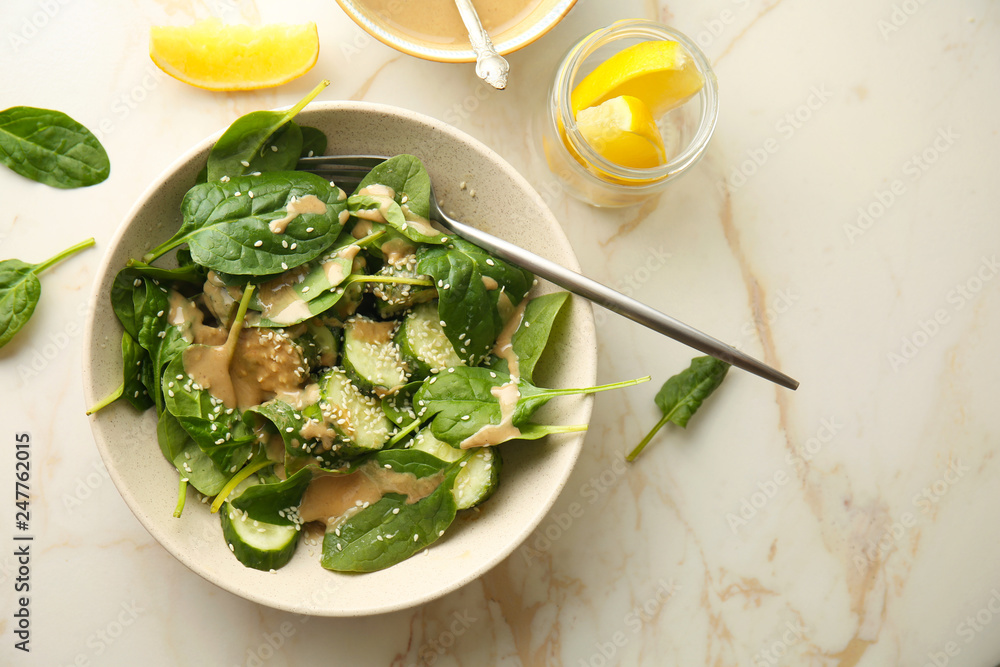 Tasty vegetable salad with tahini in bowl on light table
