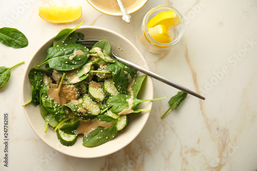 Tasty vegetable salad with tahini in bowl on light table photo