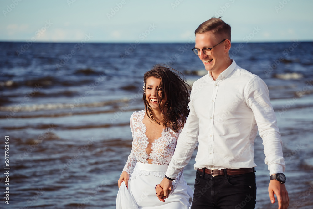 Happy young romantic cheerful loving wedding couple walking on the beach of sea. Happiness, couple, love concept