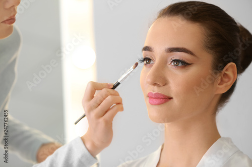 Professional makeup artist working with young bride at home