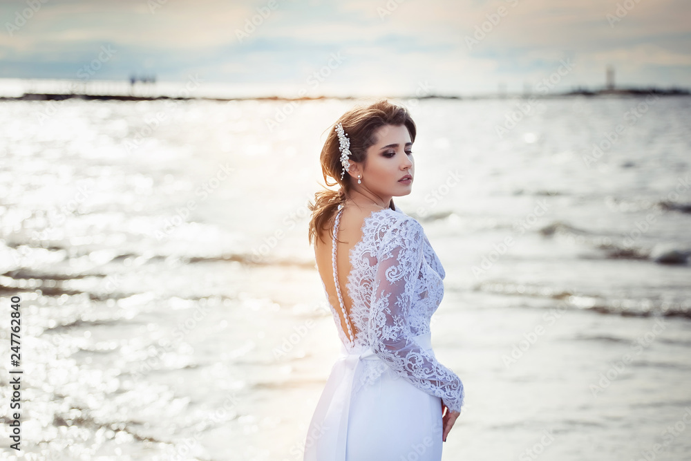 Fashionable bride in elegant wedding dress walking on the coast of ocean. Beauty, emotional, lifestyle concept Fashionable bride in elegant wedding dress walking on the coast of ocean. Beauty, emotional, lifestyle concept