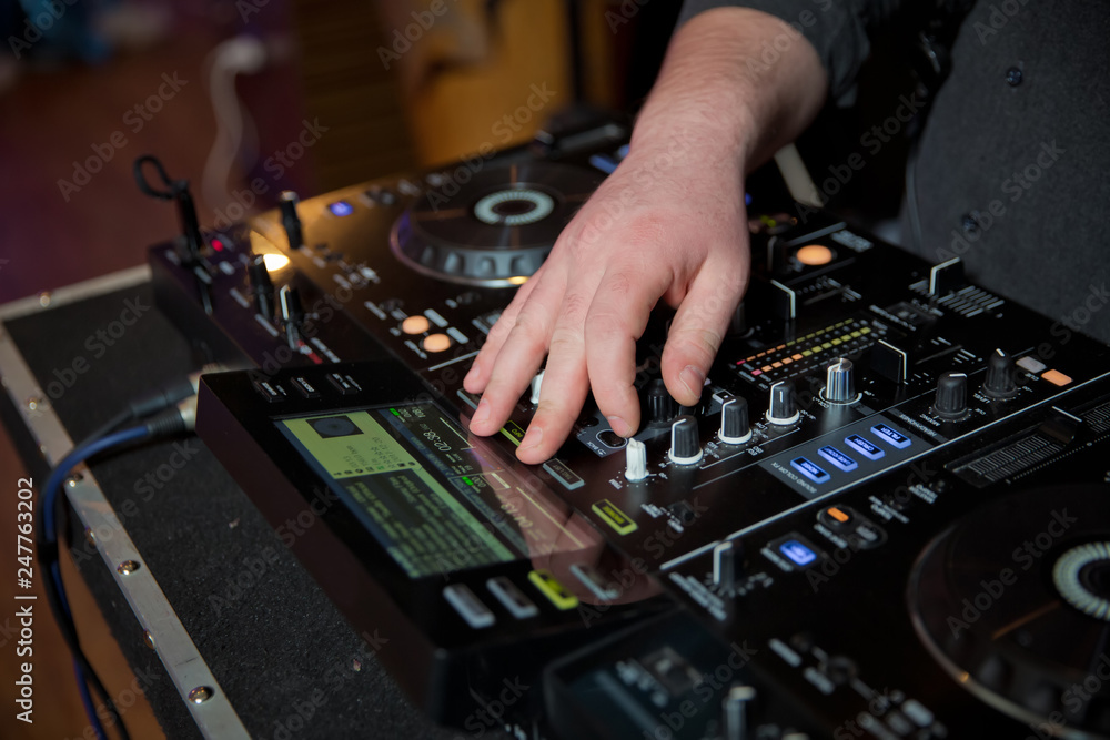 professional music equipment for mixing music in nightclub with hand of DJ . Dj mixes the track in the nightclub at party professional music equipment for mixing music in nightclub with hand of DJ . Dj mixes the track in the nightclub at party