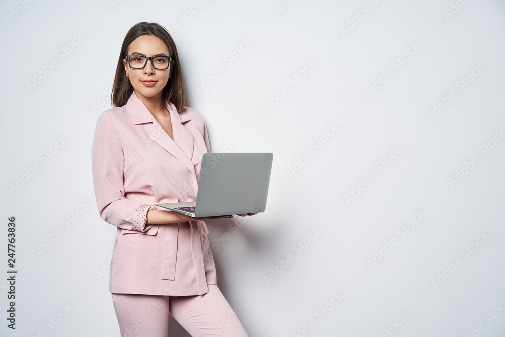 Confident business woman wearing pink suit holding opened laptop Confident business woman wearing pink suit holding opened laptop