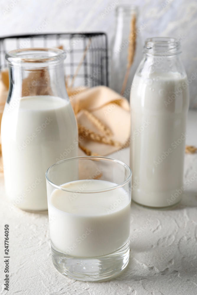 Glass and bottles of fresh milk on light table Glass and bottles of fresh milk on light table