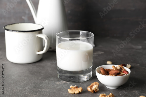 Glass of fresh milk with nuts on grey table