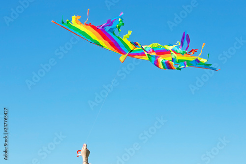 multi-colored kite flying on a blue sky background on a Sunny summer day