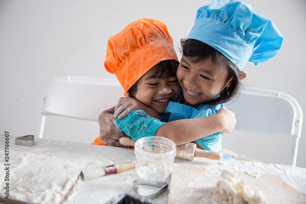two happy toddler embracing each other while make cookies together wearing apron two happy toddler embracing each other while make cookies together wearing apron