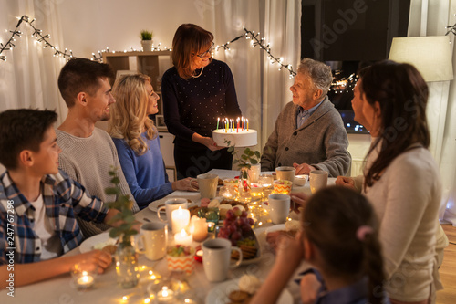 Photography dinner party and celebration concept - happy family with cake celebrating grandf