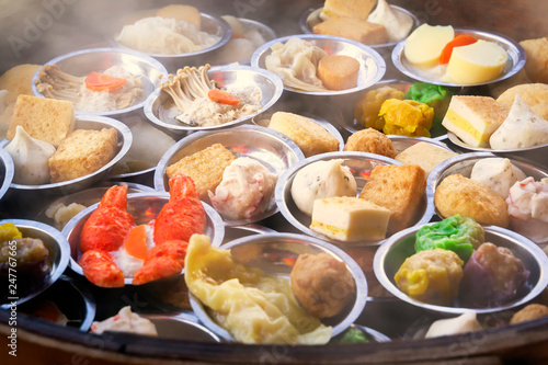 Traditional Asian dishes steamed in a bamboo basket - vegetables, mushrooms, shrimps, dough. Street food.