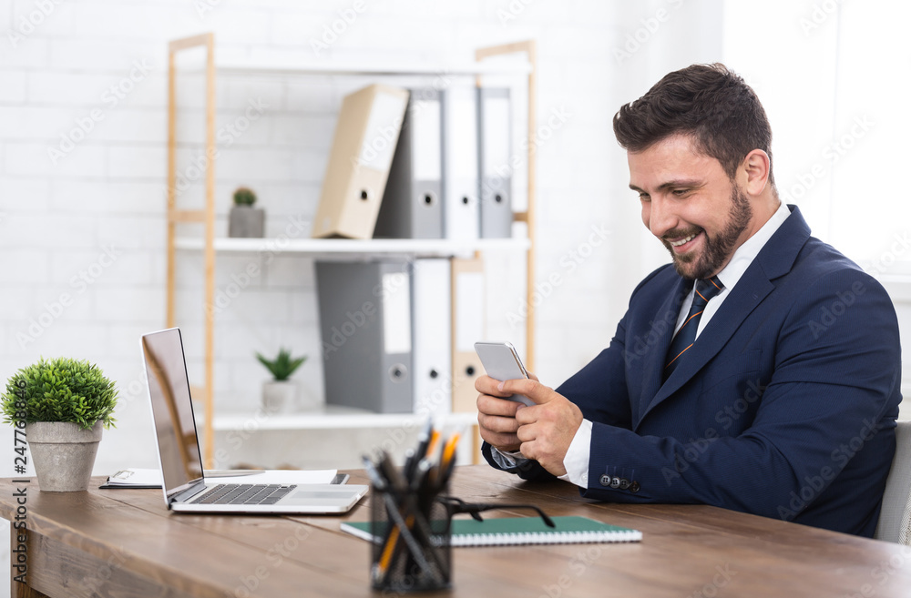 Buinessman texting on smartphone, working in office Buinessman texting on smartphone, working in office
