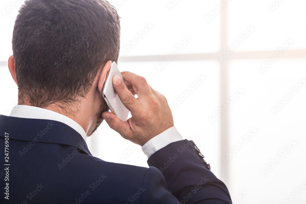 Businessman in suit talking on mobile phone, back view Businessman in suit talking on mobile phone, back view
