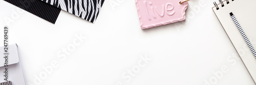 A creative desk with school supplies. Notebooks, pencils, papers in a zebra texture. Panoramic copy space for text. Black and white composition with pink elements