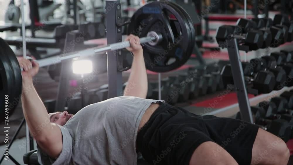 Handsome athletic man performs bench press on the bench in the gym. Handsome athletic man performs bench press on the bench in the gym.