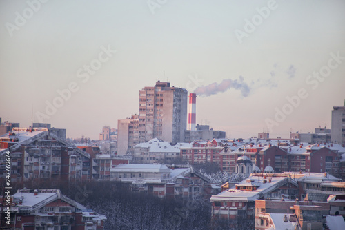 Smoking from industrial chimneys of heating plant emits smoke, smog at sunset in city, pollutants enter atmosphere. Environmental disaster. Harmful emissions, exhaust gases into air. Heating season.
