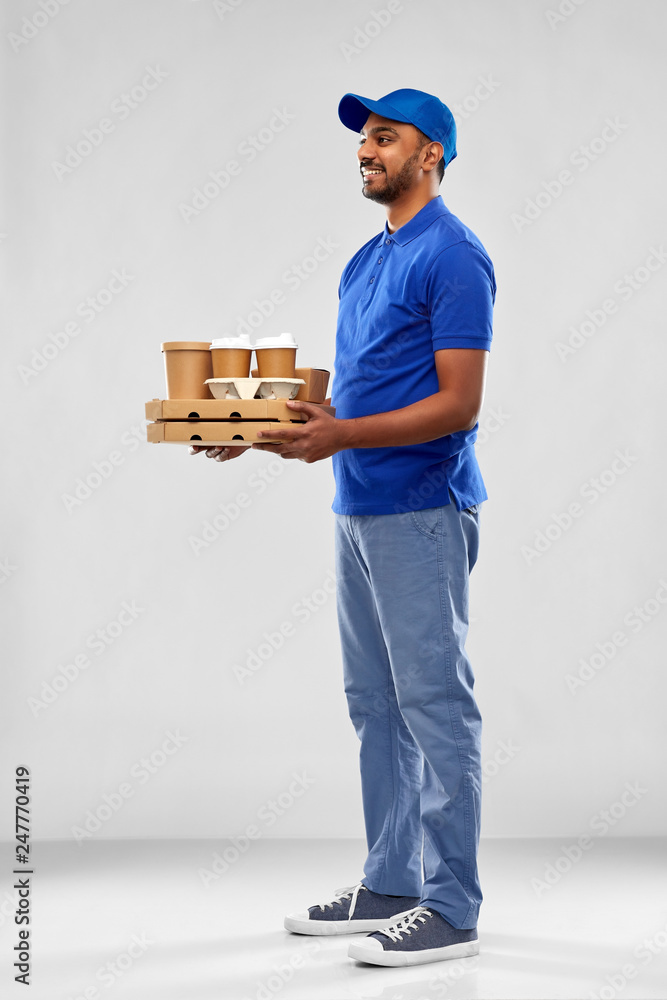 service and people concept - happy indian delivery man with food and drinks in blue uniform over grey background service and people concept - happy indian delivery man with food and drinks in blue uniform over grey background